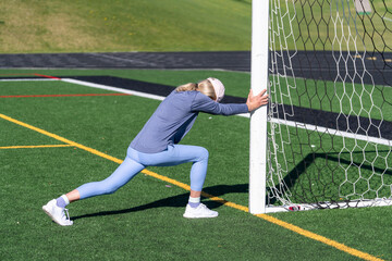Woman performing stretching and warm-up on a soccer and football field
