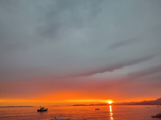 Dramatic Sunset with Stormy Clouds Over Calm Sea and Boats