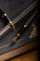 Fountain pen, two beautiful fountain pens with books on a rustic wooden surface, selective focus.