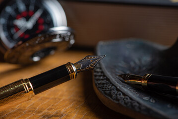 Naklejka premium Fountain pen, two beautiful fountain pens with books on a rustic wooden surface, selective focus.
