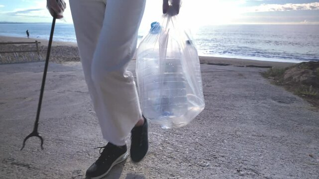 A woman takes a full bag with plastics and bottles that she has collected to avoid pollution of the environment.