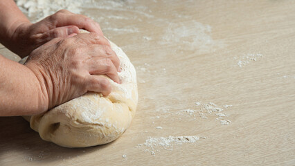 Raw homemade bread, preparing and kneading the bread before baking, on a wooden surface, selective focus.