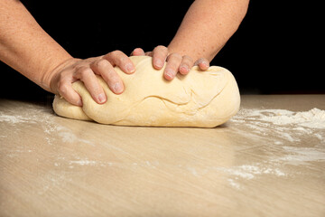 Raw homemade bread, preparing and kneading the bread before baking, on a wooden surface, selective focus.