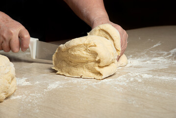 Raw homemade bread, preparing and kneading the bread before baking, on a wooden surface, selective...