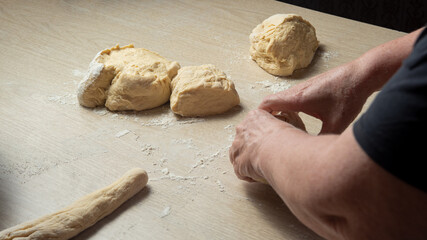 Raw homemade bread, preparing and kneading the bread before baking, on a wooden surface, selective focus.