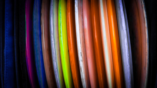macro close-up of colorful weathered disc golf discs stored vertically. abstract sports recreation background or banner