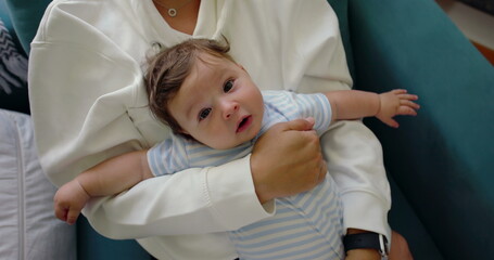 Close-up of baby lying comfortably on mother's lap, being held with care and affection in a warm...