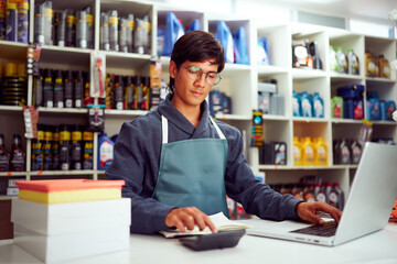Shopkeeper calculating and working on laptop in auto store