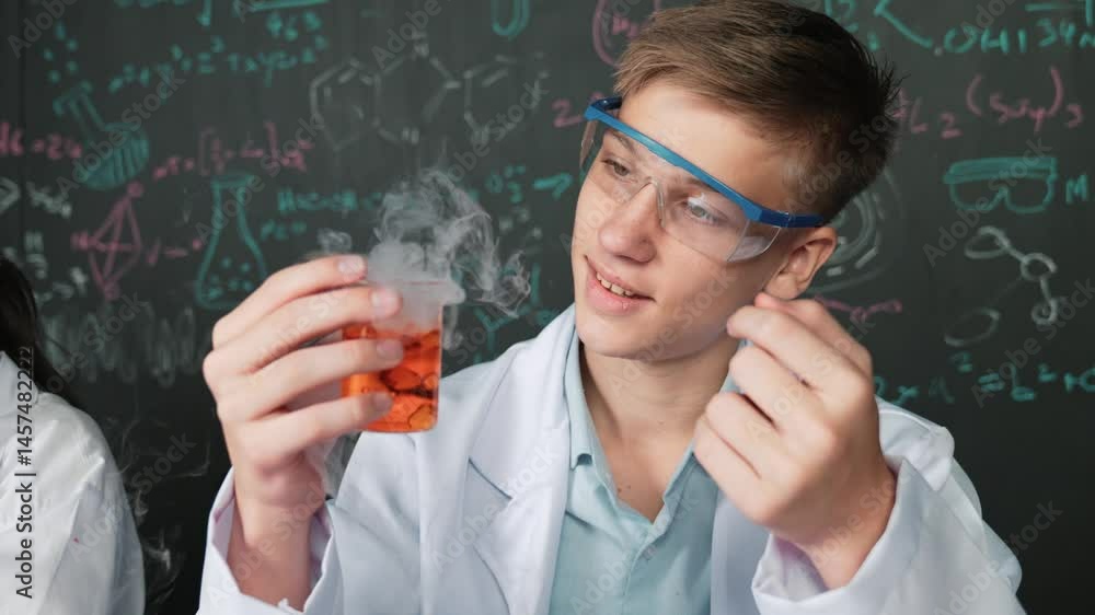 Poster closeup of boy inspect chemical solution while holding beaker at blackboard with chemical theory. sm