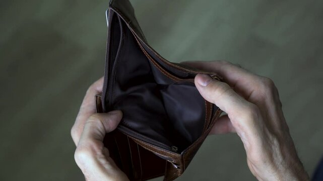 Close-up of man checking empty wallet in financial distress