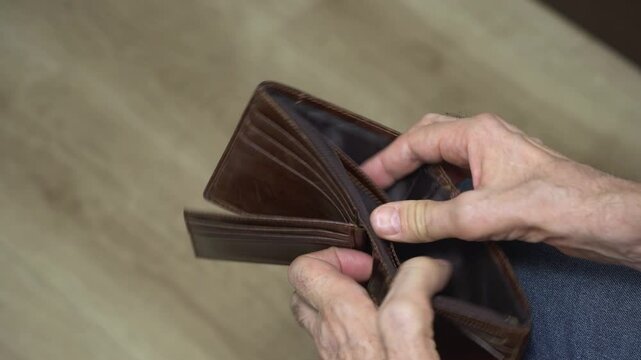 Close-up of man on floor opening empty brown wallet
