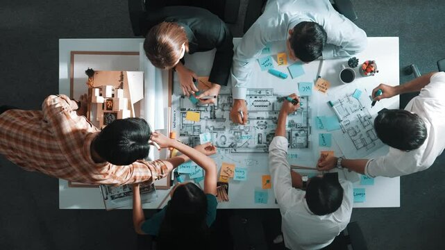 Top aerial view of project manager or civil engineer writing at blueprint and planning building design. Aerial view of architect working together at meeting table with document placed. Alimentation.