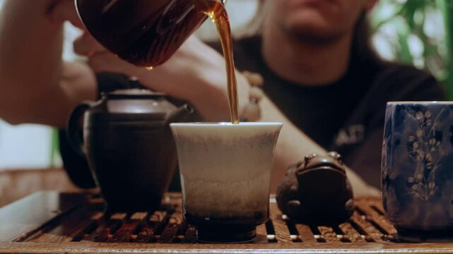 This calm and intentional moment shows the final step in a tea ritual &mdash; serving tea into bowls for tasting.