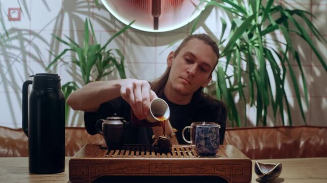 A tea ceremony master pours brewed tea onto a clay frog, a symbolic gesture of respect and tradition in Chinese tea culture.