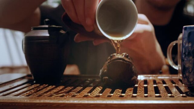 A meaningful act in a Chinese tea ceremony as the tea master honors tradition by pouring brewed tea over a small clay frog.