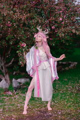 Deer dryad girl against the background of a blooming pink apple tree