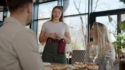 Young waitress taking order and having friendly conversation with restaurant customers