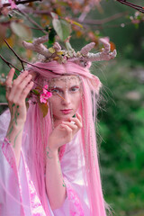 Deer dryad girl against the background of a blooming pink apple tree