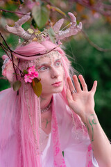 Deer dryad girl against the background of a blooming pink apple tree