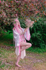 Deer dryad girl against the background of a blooming pink apple tree