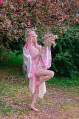 Deer dryad girl against the background of a blooming pink apple tree