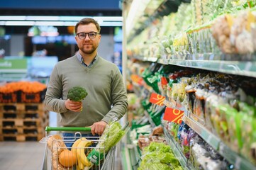 A man with a cart walks in a supermarket