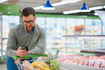 Young man buying groceries at the supermarket. Consumerism concept