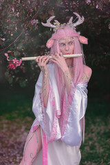 Deer dryad girl against the background of a blooming pink apple tree