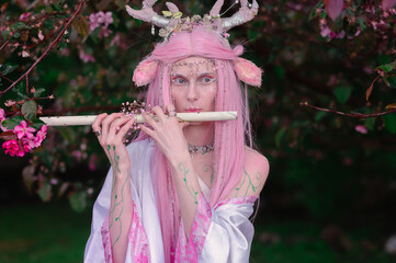 Deer dryad girl against the background of a blooming pink apple tree