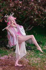 Deer dryad girl against the background of a blooming pink apple tree