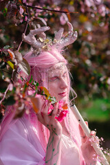 Deer dryad girl against the background of a blooming pink apple tree