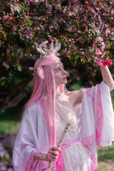 Deer dryad girl against the background of a blooming pink apple tree