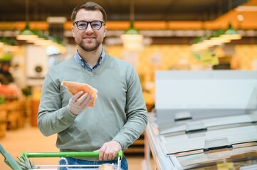 Young man buying groceries at the supermarket. Consumerism concept