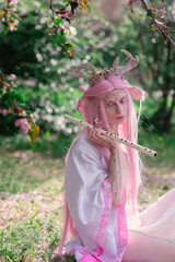 Deer dryad girl against the background of a blooming pink apple tree