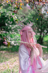 Deer dryad girl against the background of a blooming pink apple tree