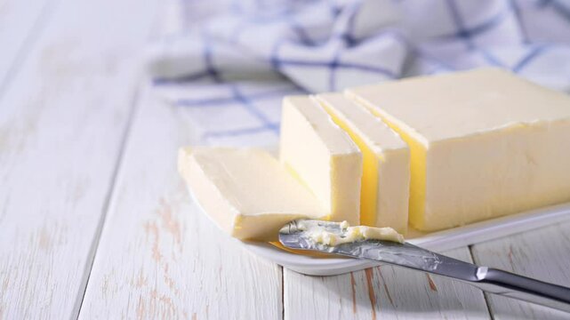 piece of butter in a white ceramic butter dish on a light table.
    Block of fresh butter in a white dish on a kitchen table .