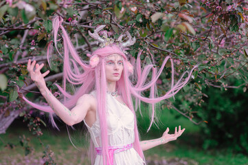Deer dryad girl against the background of a blooming pink apple tree