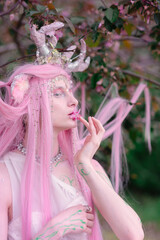 Deer dryad girl against the background of a blooming pink apple tree