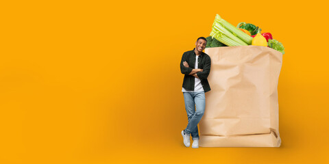 A customer stands beside a large paper bag filled with fresh vegetables, showcasing the current...