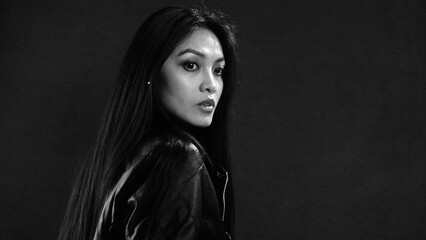 Woman in leather jacket gazing intensely in monochrome setting