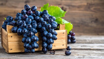 Ripe, dark grapes spill from a rustic wooden crate, showcasing a bountiful harvest and autumnal abundance on a weathered surface.