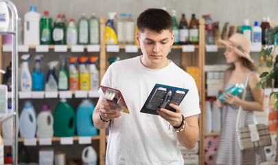 Guy examines product shaver set while purchase in store. Customer near display case looks at...