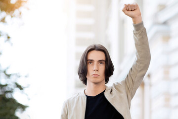 Young man leading international group of students, raising fist up and looking at camera. Male...
