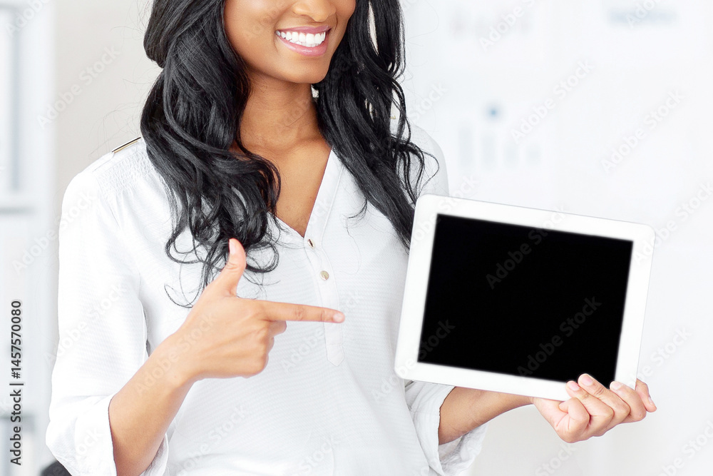 Poster smiling black business lady pointing at tablet computer with blank screen at office, mockup for app 