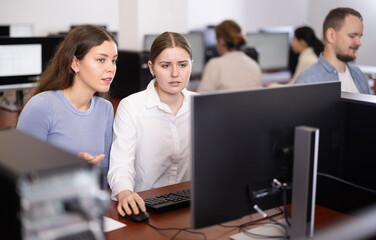 Female teacher of computer courses helps girl student to figure out with performance of difficult...