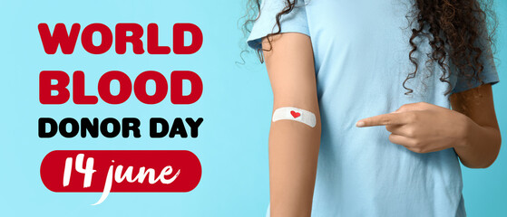 Young female African-American blood donor pointing at applied medical patch on blue background