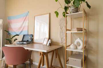 Interior of living room with transgender flag, shelf unit and workplace