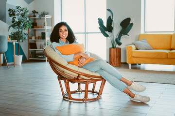 Attractive young woman relaxing comfortably in a modern interior living room setting with natural lighting and contemporary decor elements