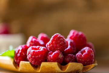 Spoon with raspberry and bowl with raspberry jam on wooden background