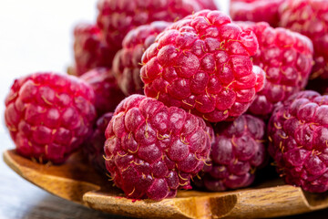 Spoon with raspberry and bowl with raspberry jam on wooden background
